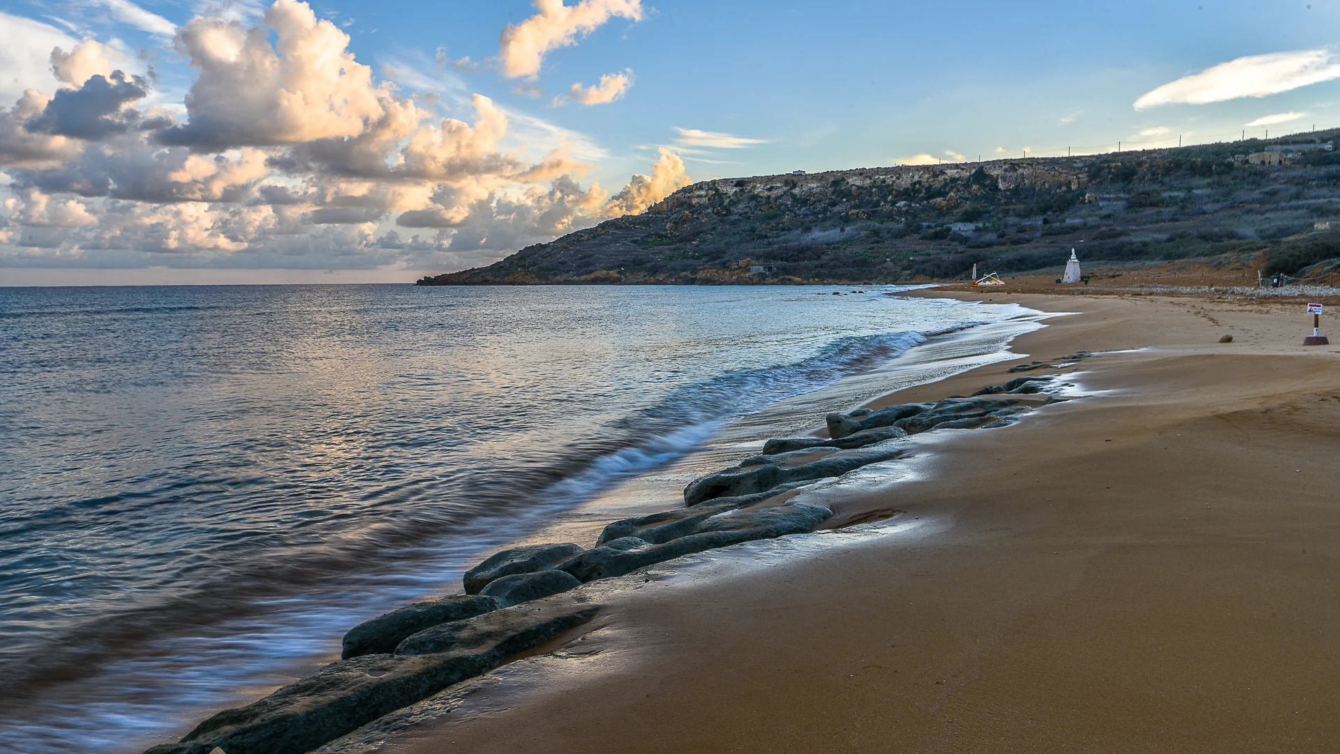 The red-gold sand and calm bay of Ramla Bay on Gozo, near the island's farmhouse-villa villages