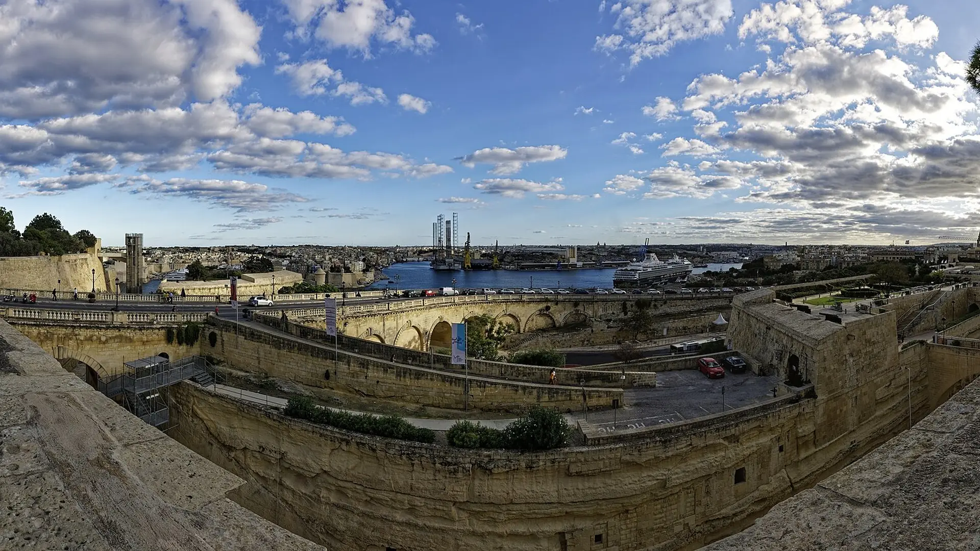 A 360-degree panorama of Valletta's Grand Harbour from St James Bastion, with the fortified walls and golden limestone buildings